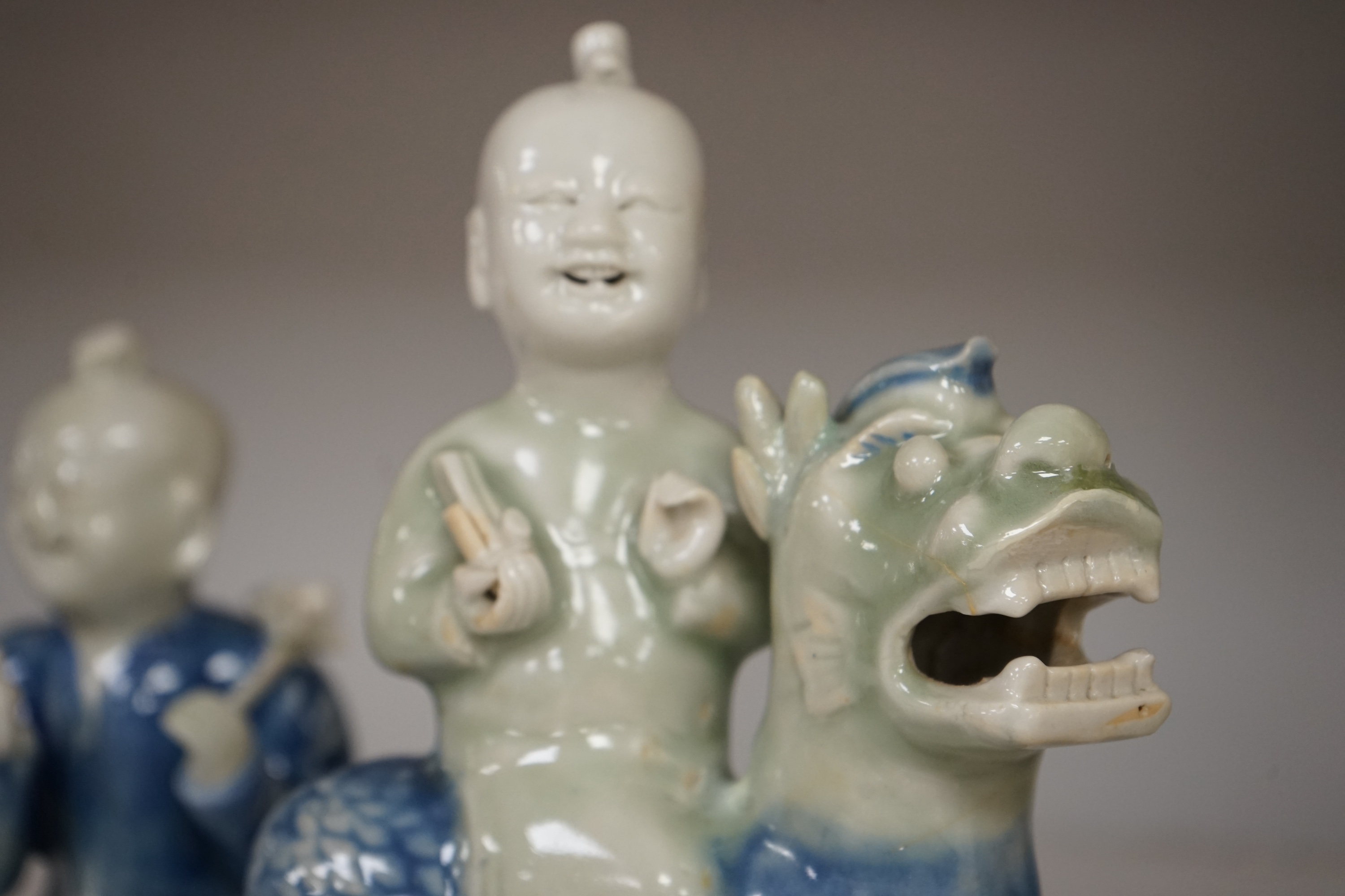 Three Chinese celadon and blue glazed porcelain boy figures, 18th century, largest 20cm high. Condition - fair, all restored